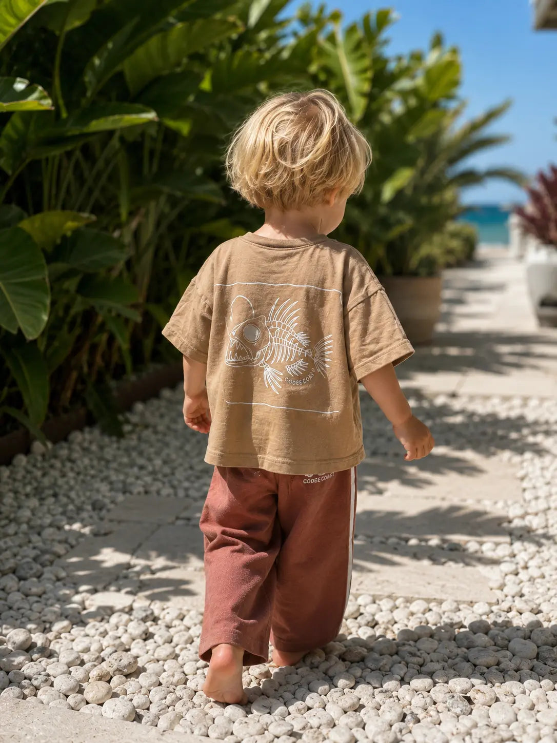 Back view of boy wearing Cooee Coast, coastal flow tee featuring angler back print