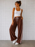 Woman wearing Cooee Coast Chocolate terry pants featuring embroidered back pocket, relaxed fit.