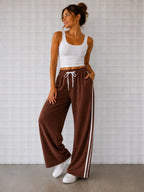 Woman wearing Cooee Coast Chocolate terry pants featuring embroidered back pocket, relaxed fit.