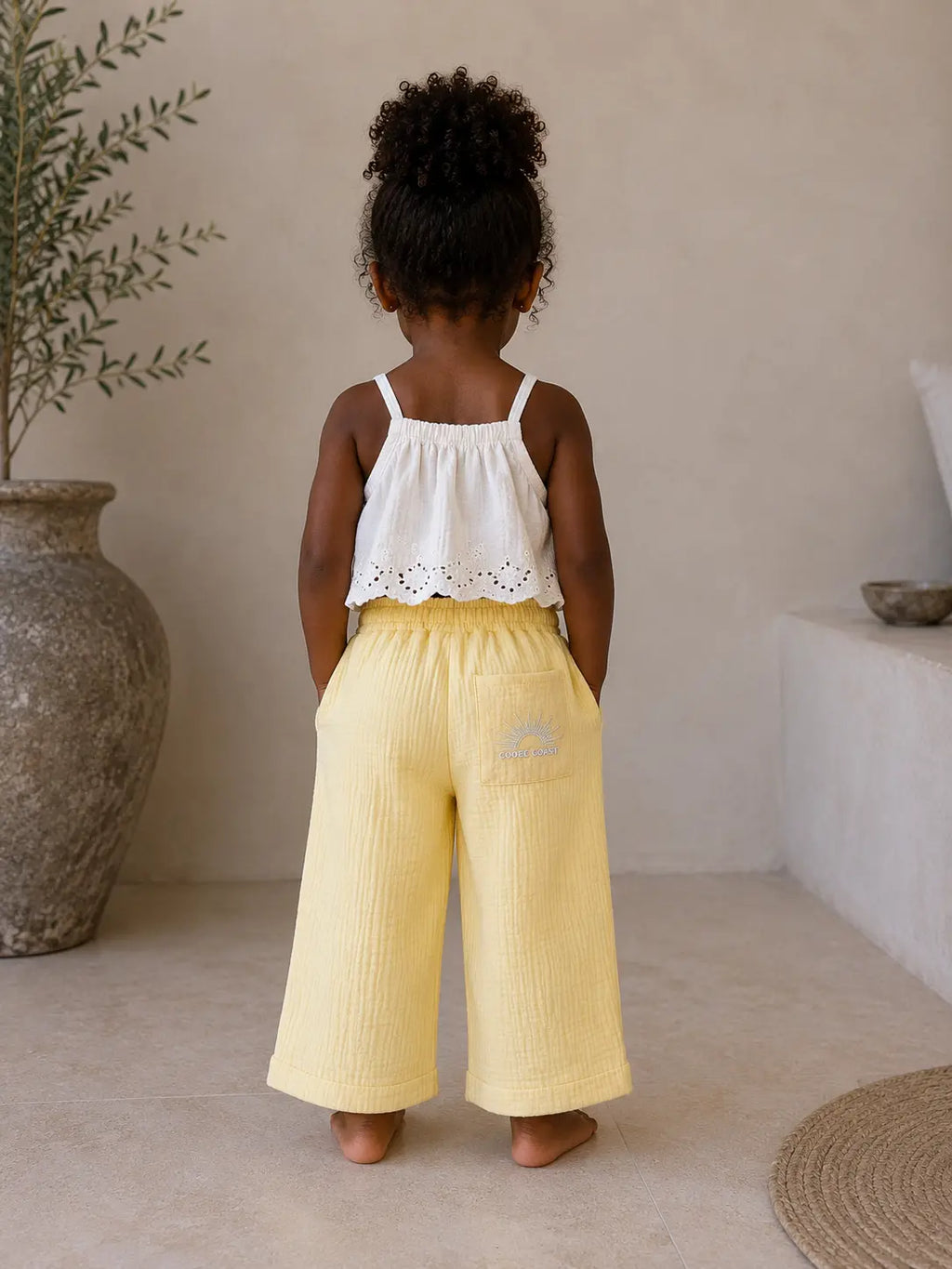Back view of girl wearing Cooee Coast Lemon coastal dune pants featuring embroidered back pocket, relaxed fit.