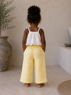 Back view of girl wearing Cooee Coast Lemon coastal dune pants featuring embroidered back pocket, relaxed fit.
