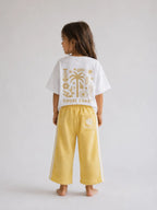 Back view of girl wearing Cooee Coast lemon sorbet retro terry pants featuring embroidered back pocket, relaxed fit.