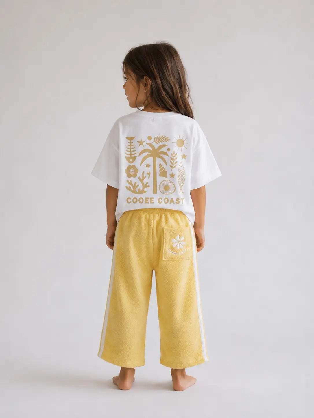 Back view of girl wearing Cooee Coast lemon sorbet retro terry pants featuring embroidered back pocket, relaxed fit.