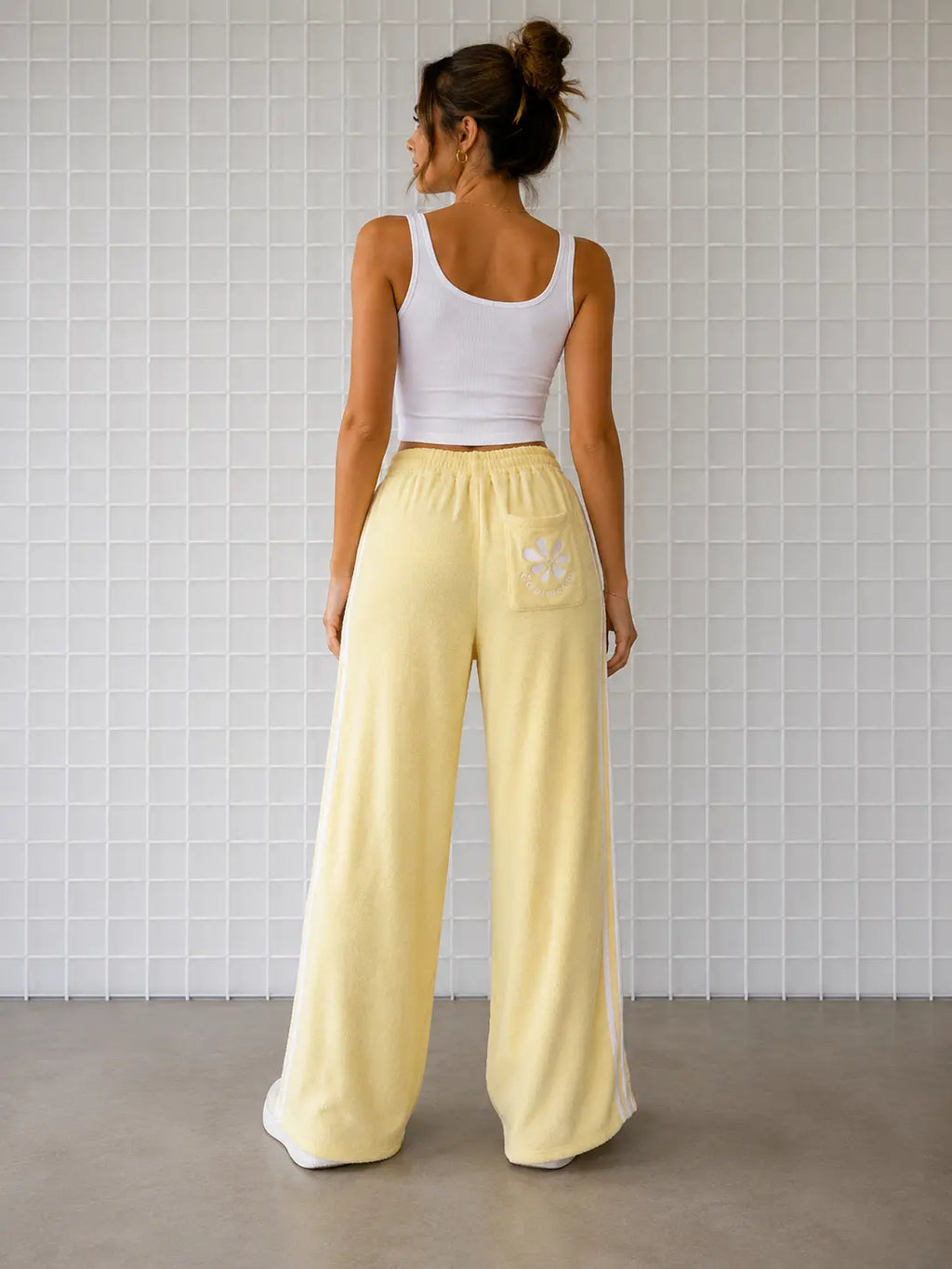 Backview of woman wearing Cooee Coast Lemon retro terry pants featuring embroidered back pocket, relaxed fit.