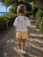 Back view of a girl wearing Cooee Coast Lemon Sorbet terry shorts featuring embroidered back pocket, relaxed fit.