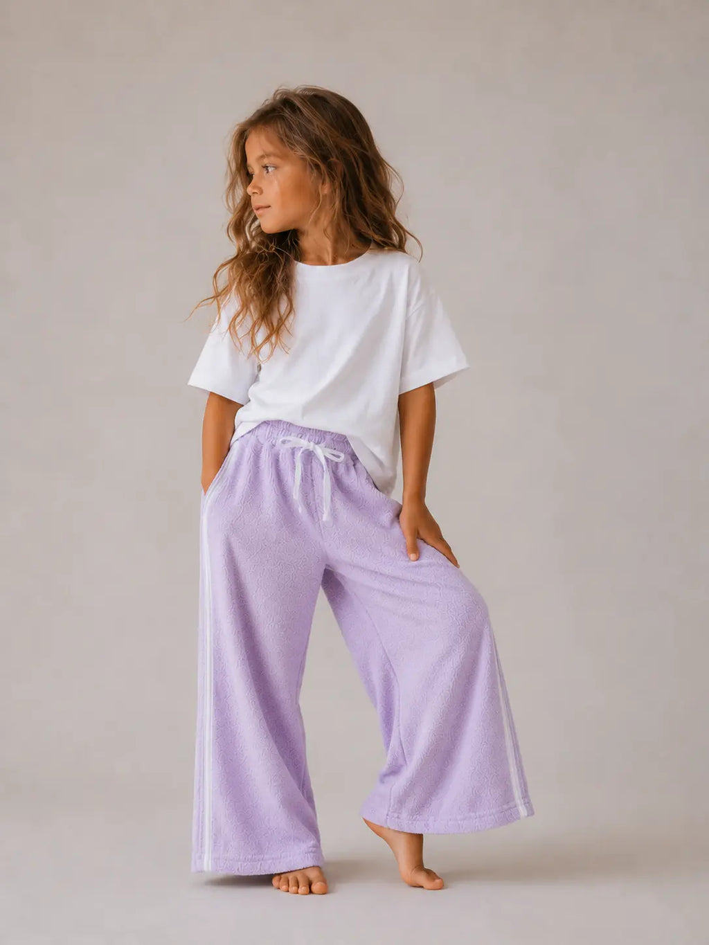 Girl wearing Cooee Coast lilac retro terry pants featuring embroidered back pocket, relaxed fit.