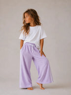 Girl wearing Cooee Coast lilac retro terry pants featuring embroidered back pocket, relaxed fit.