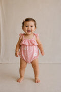 Baby wearing Cooee Coast Poppy Romper featuring floral print and adjustable tie straps