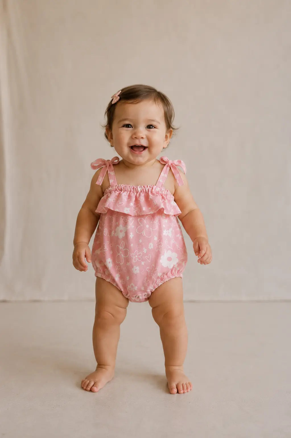 Baby wearing Cooee Coast Poppy Romper featuring floral print and adjustable tie straps