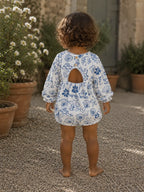 Back:
Back view of baby wearing Cooee Coast Amore Romper featuring open back and wooden button detail.